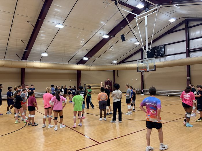 A large group of athletes gathered on the court at a clinic