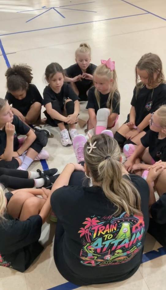 A coach sitting knee-to-knee with a circle of young athletes during a team talk