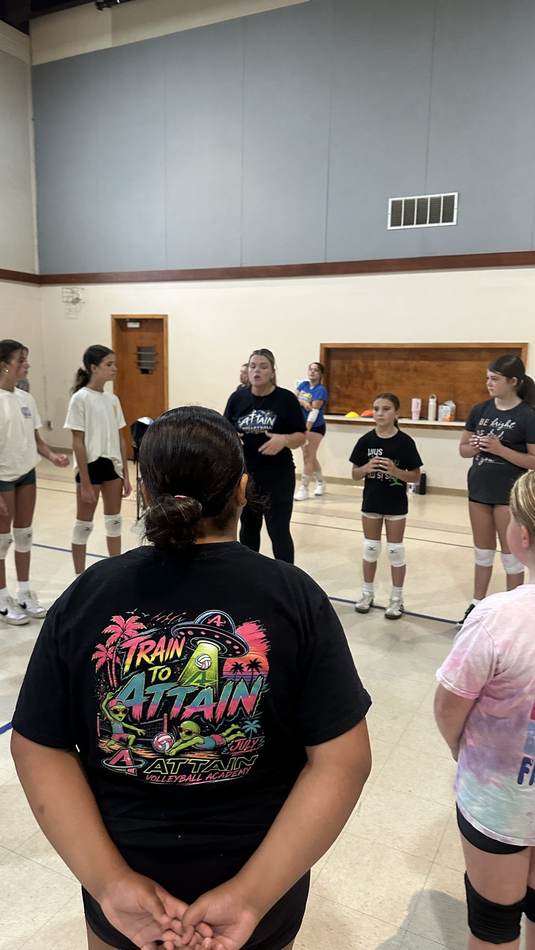 Athletes gathered around a coach for instruction before a training session
