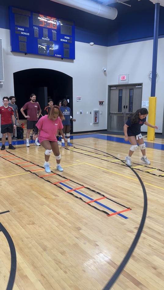 Two athletes running an agility ladder drill during conditioning work